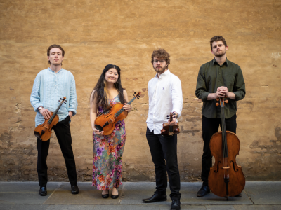 Picture of Elmore string quartet holding instruments against brick wall